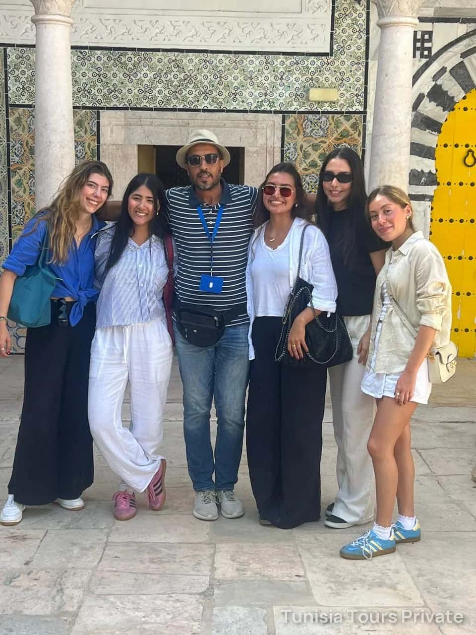 Un guía y sus viajeros ante una puerta de azulejos en la medina
