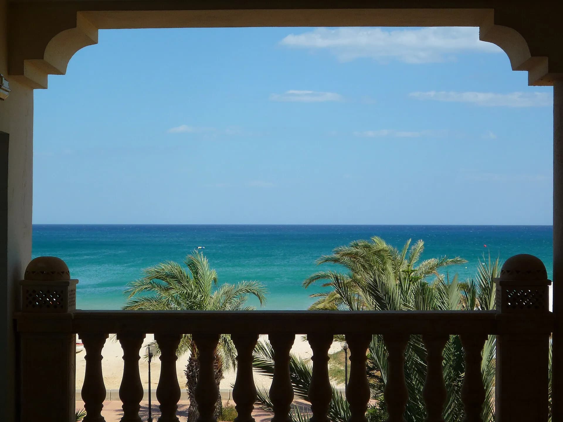 The sea and palm trees of Hammamet seen through a carved window