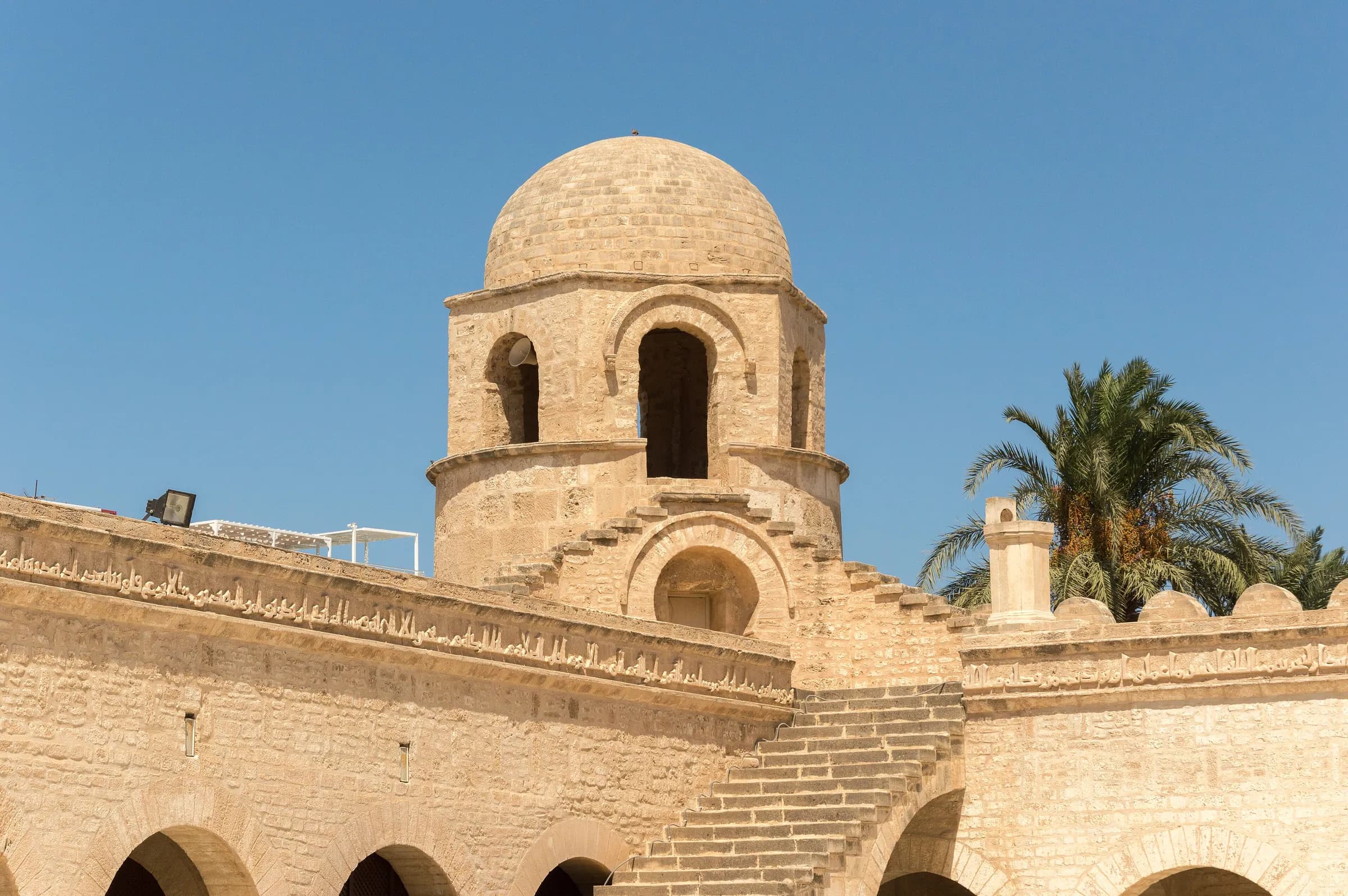 The domed tower of the Great Mosque of Sousse against a blue sky